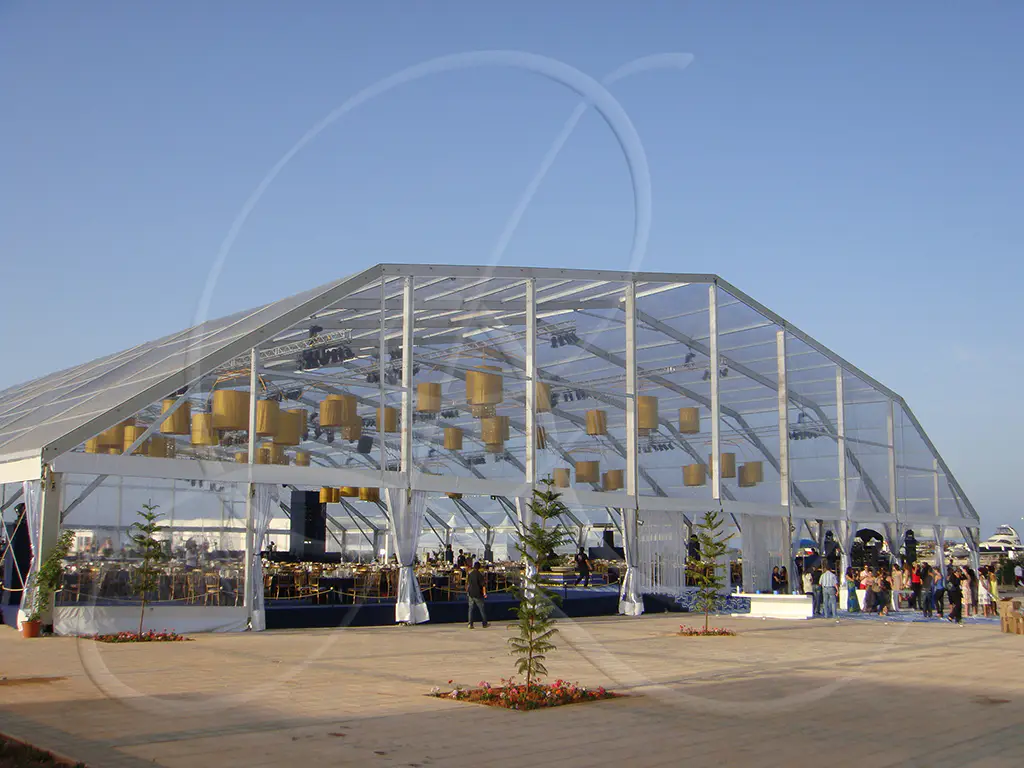 Large transparent event marquee installed by the sea, a Rahal Maître Traiteur deployment